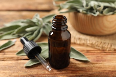 Photo of Bottle of essential sage oil, dropper and leaves on wooden table.