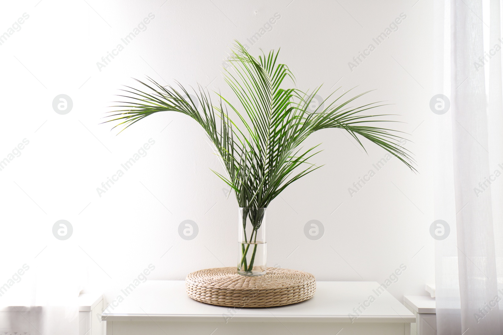 Photo of Green tropical leaves in vase on table. Modern decor for stylish interior