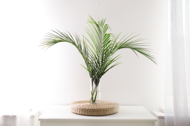 Photo of Green tropical leaves in vase on table. Modern decor for stylish interior