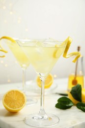 Photo of Delicious bee's knees cocktail with ice and lemon twist on white table