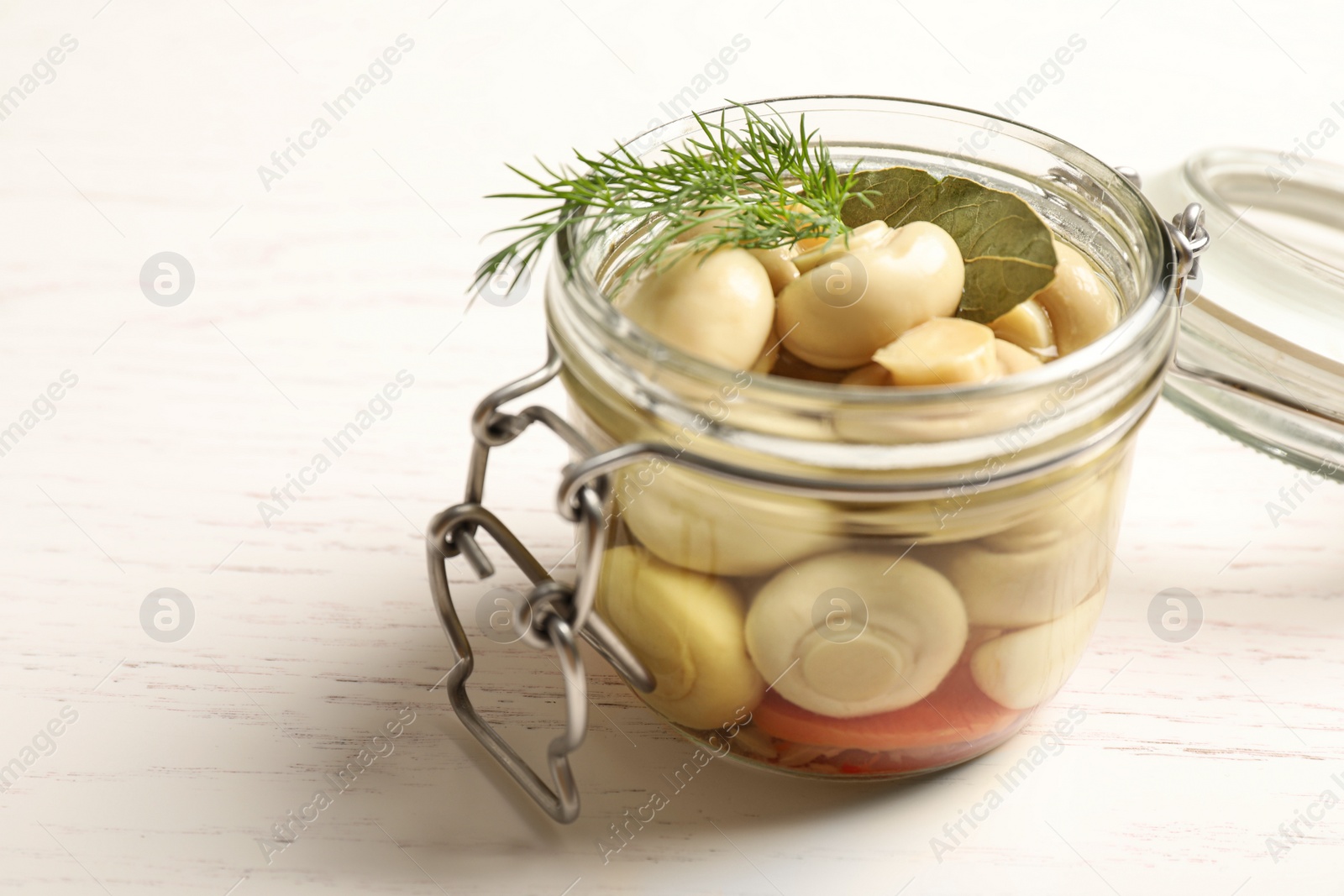 Photo of Jar with marinated mushrooms and dill on white wooden table, closeup. Space for text