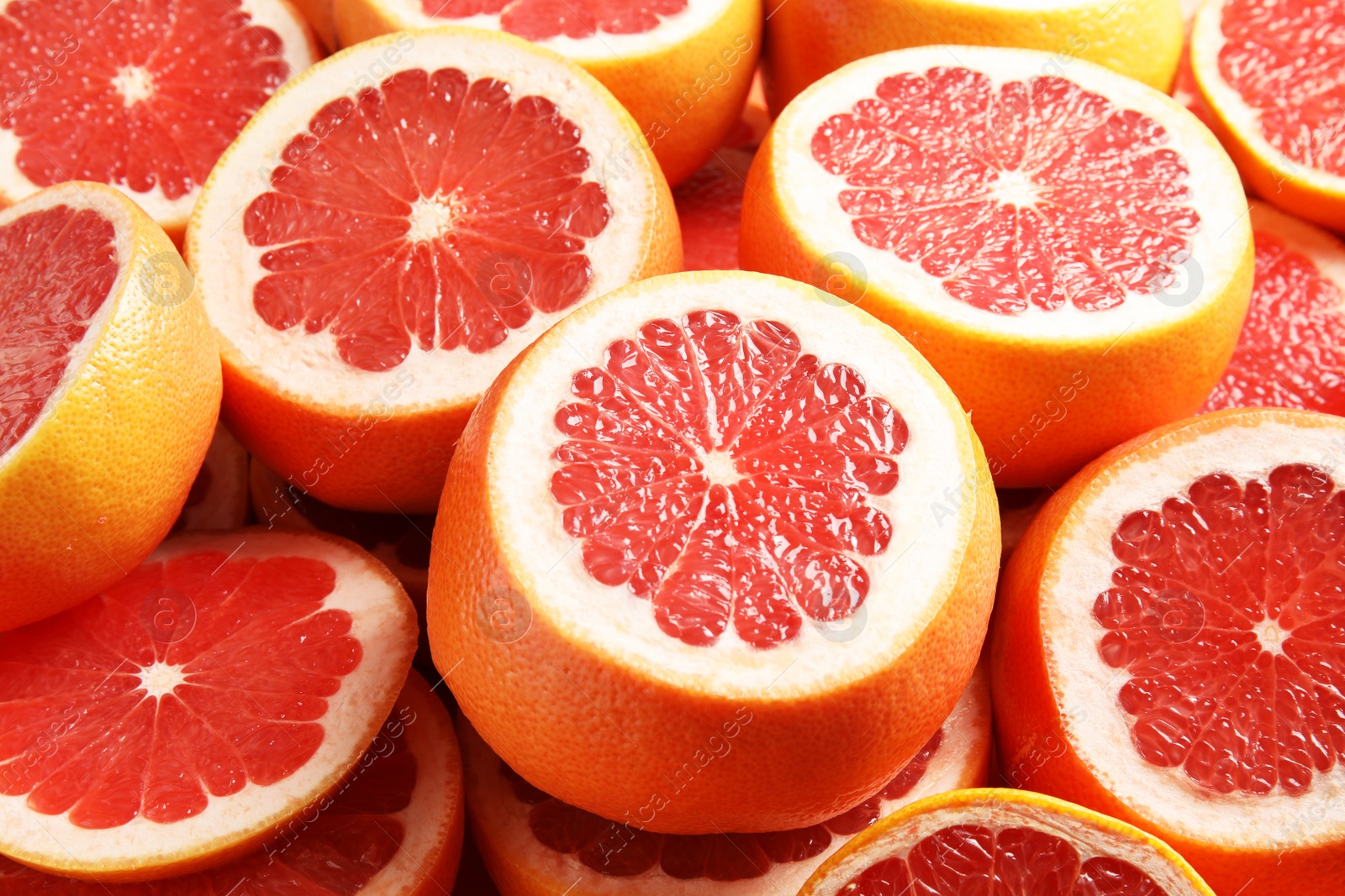 Photo of Many sliced fresh ripe grapefruits as background, closeup