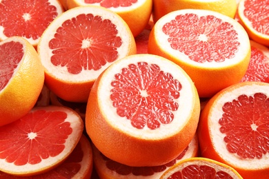 Photo of Many sliced fresh ripe grapefruits as background, closeup