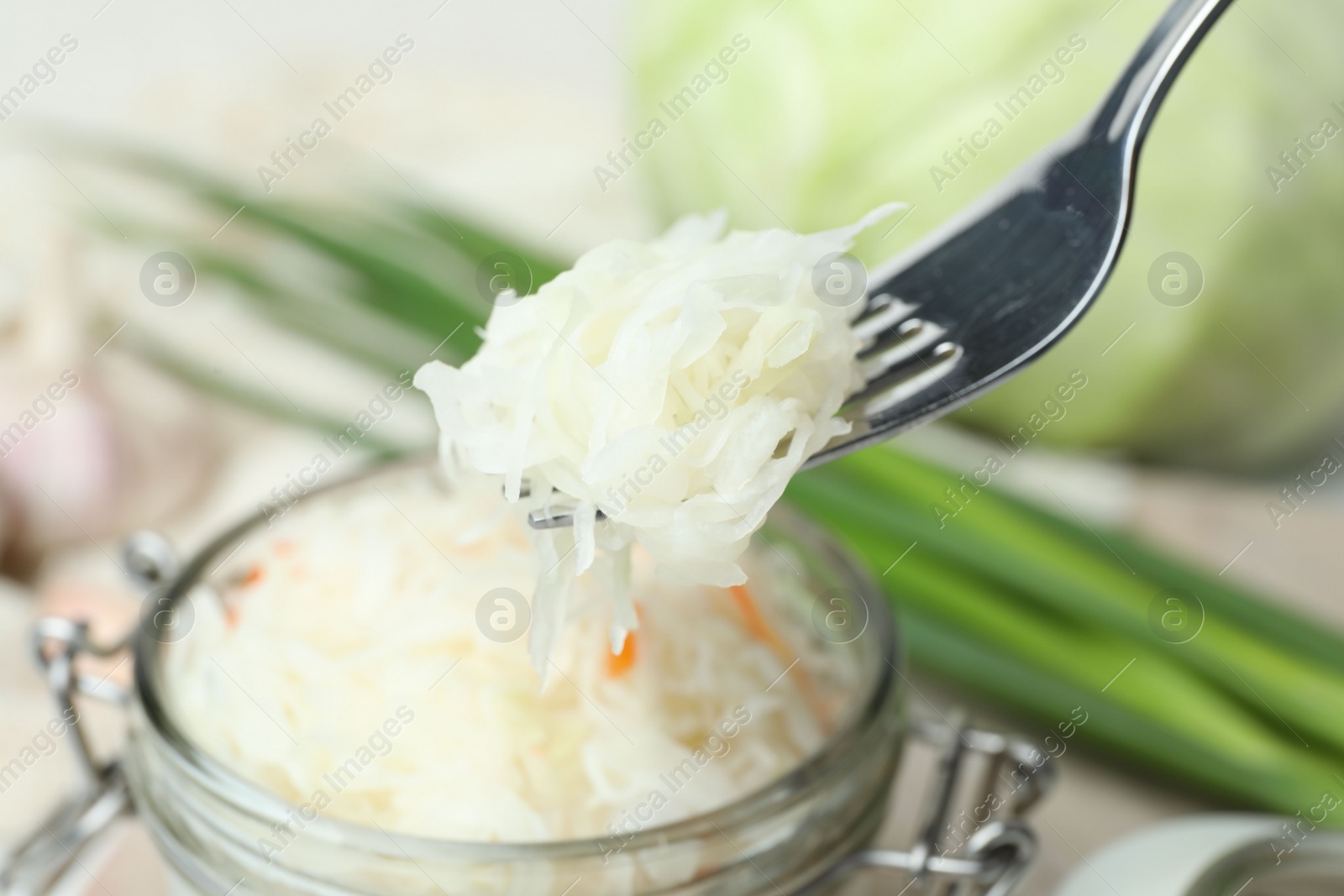 Photo of Fork with tasty fermented cabbage over jar, closeup