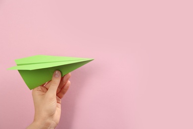 Woman holding paper plane on pink background, closeup. Space for text