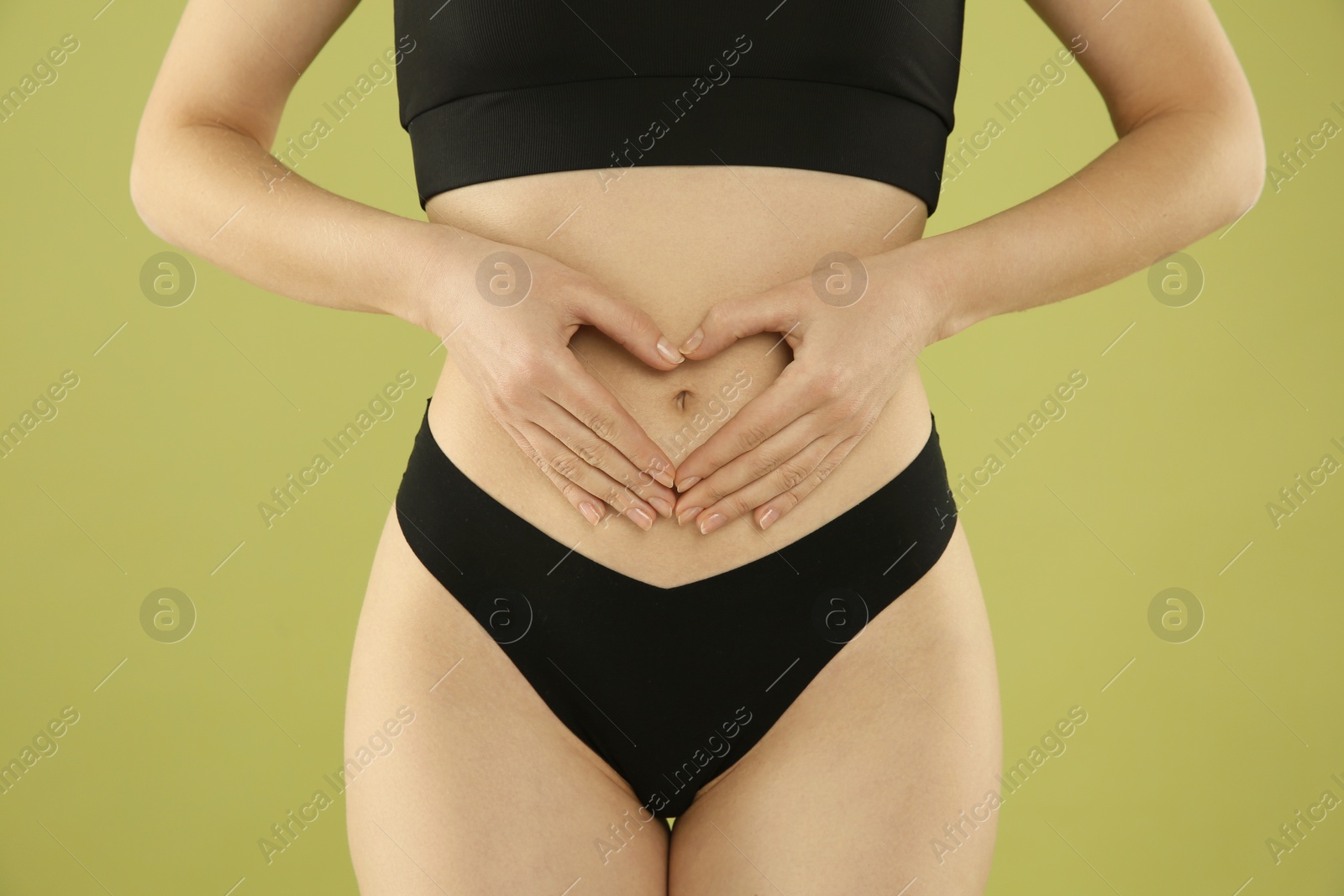 Photo of Gynecology. Woman in underwear making heart with her hands on green background, closeup