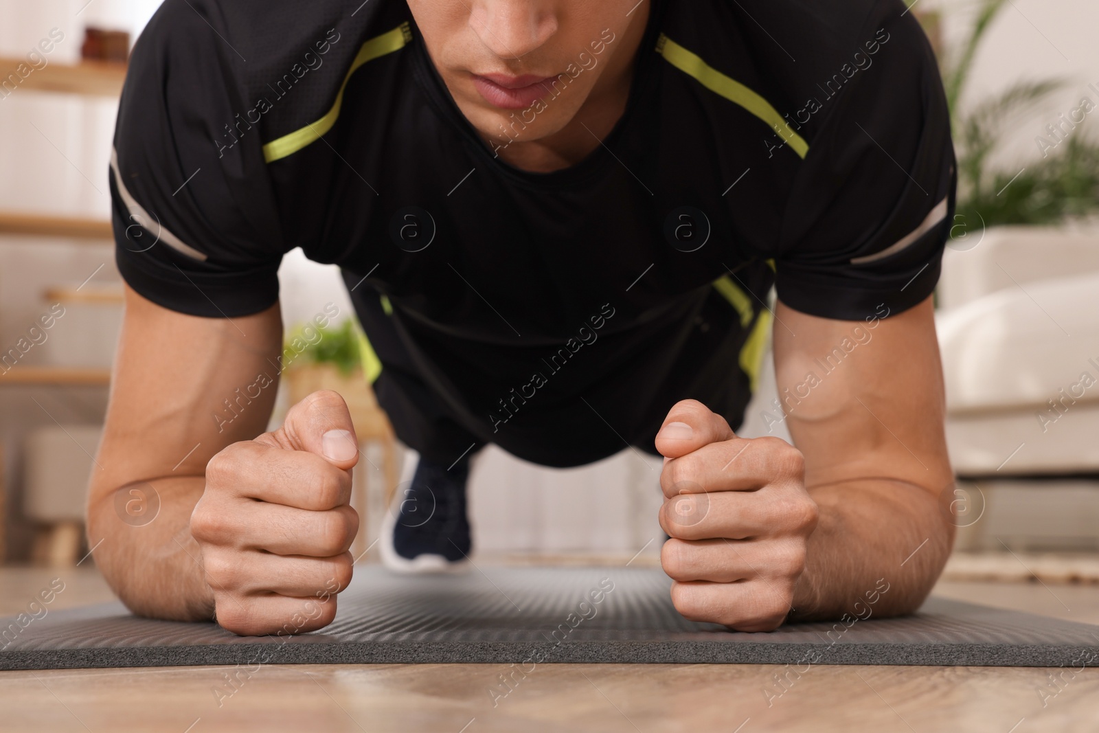 Photo of Man doing plank exercise on floor at home, closeup