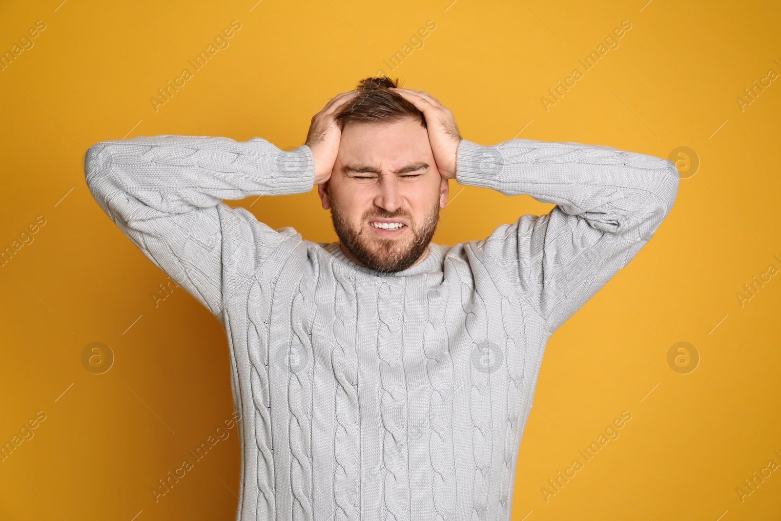 Photo of Man suffering from migraine on yellow background