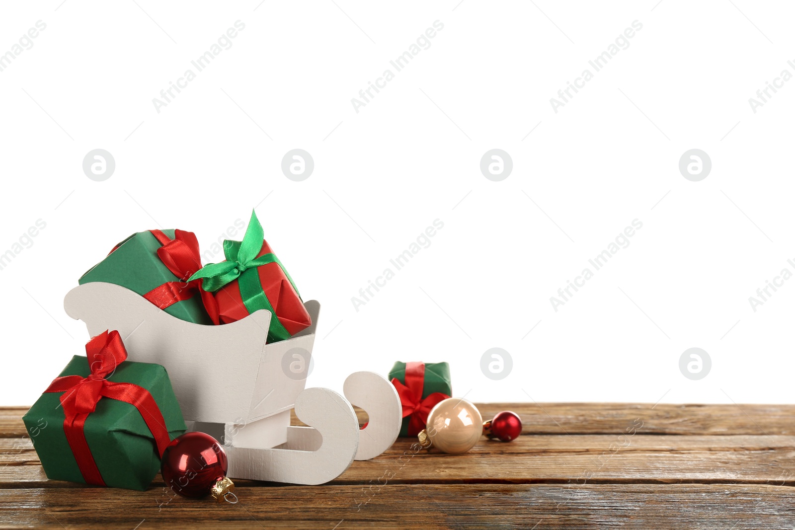 Photo of Decorative sleigh with gift boxes and Christmas balls on wooden table. Space for text