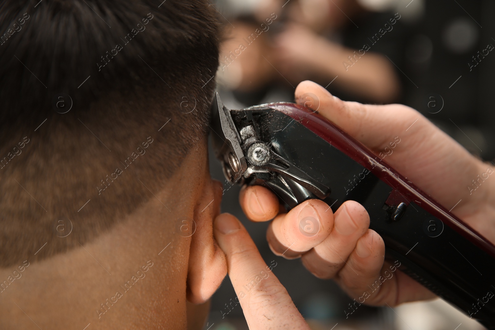 Photo of Professional barber making stylish haircut in salon, closeup