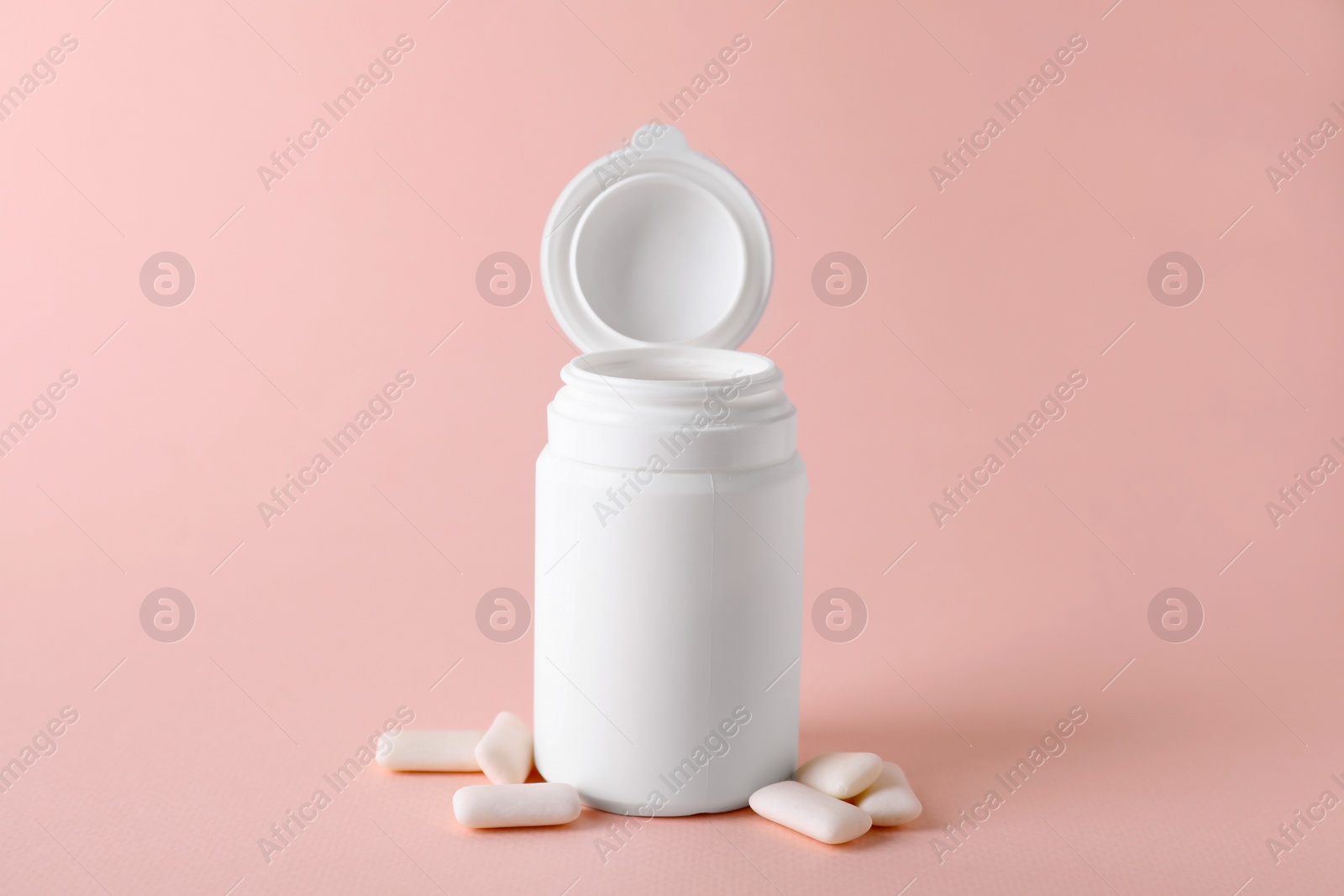 Photo of Jar with chewing gums on light pink background