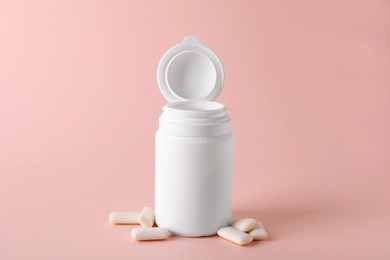 Photo of Jar with chewing gums on light pink background