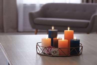 Photo of Tray with burning candles and flowers on table in living room