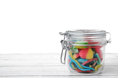 Tasty jelly candies in jar on white wooden table