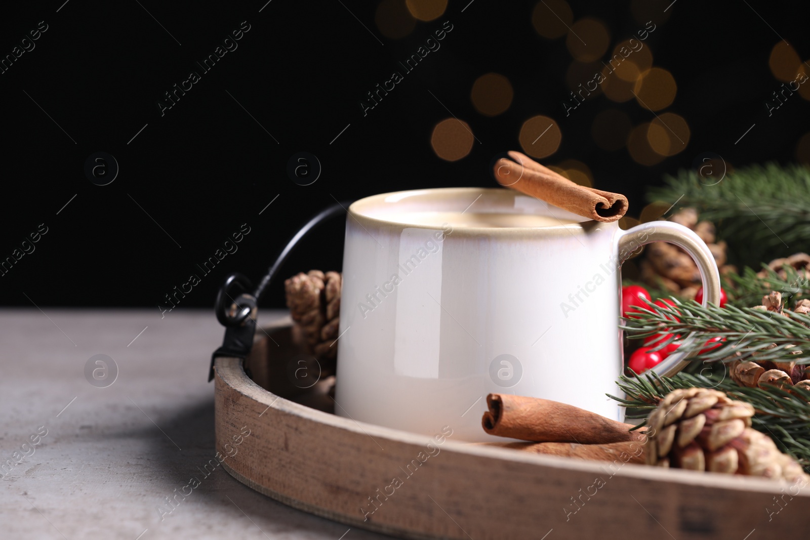Photo of Tasty eggnog with cinnamon sticks on grey textured table, closeup. Space for text