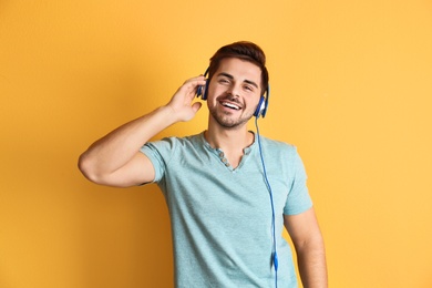 Photo of Handsome man with headphones enjoying music on color background