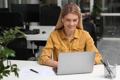 Woman working on laptop at white desk in office. Space for text