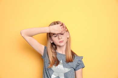 Teenage girl suffering from headache on color background