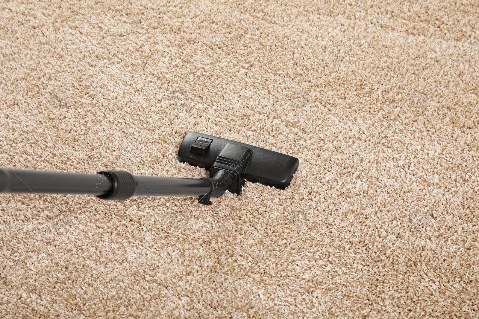 Photo of Removing dirt from beige carpet with modern vacuum cleaner, above view