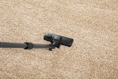 Photo of Removing dirt from beige carpet with modern vacuum cleaner, above view