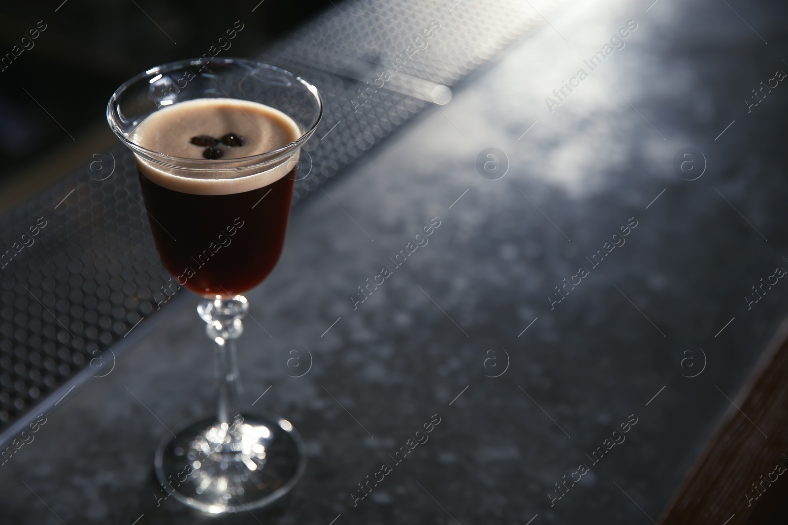 Photo of Glass of martini espresso cocktail on bar counter. Space for text