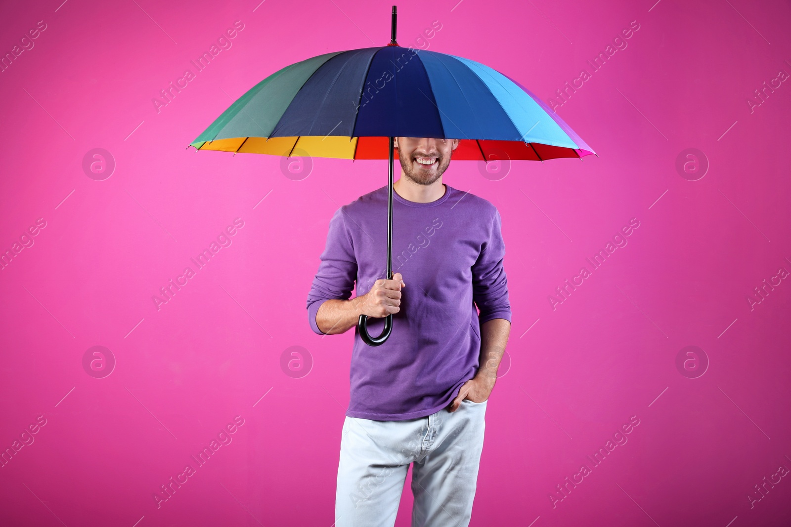 Photo of Man with rainbow umbrella on color background