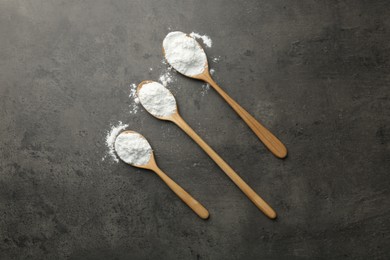 Baking powder in spoons on grey textured table, flat lay