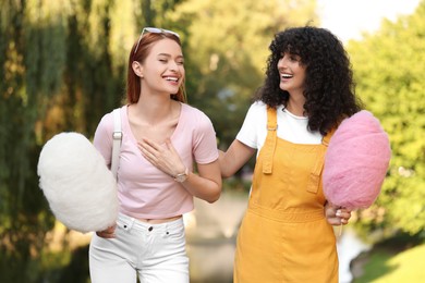 Photo of Happy friends with cotton candies spending time together in park on sunny day