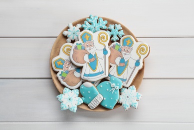 Photo of Tasty gingerbread cookies on white wooden table, top view. St. Nicholas Day celebration