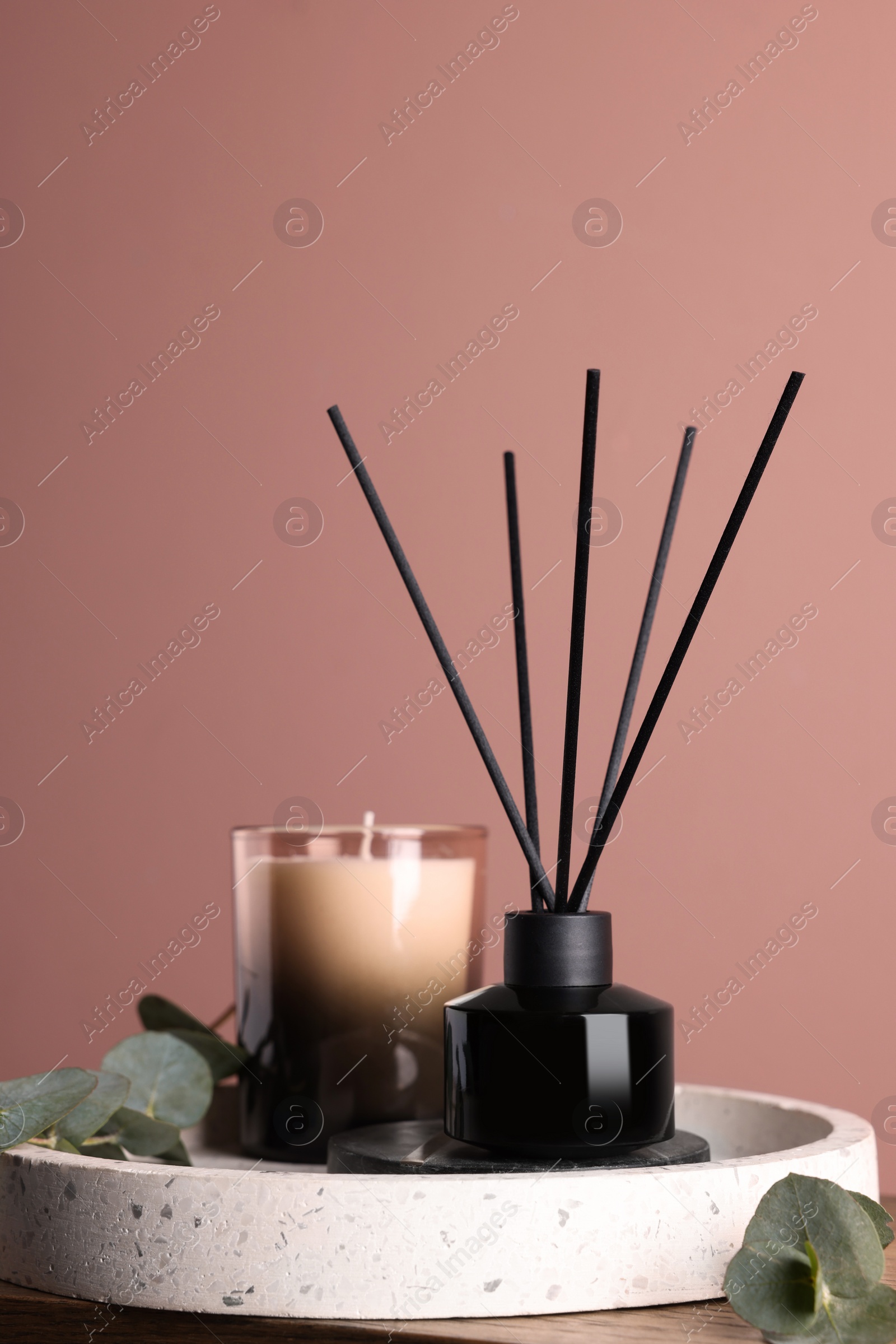 Photo of Composition with aromatic reed air freshener on wooden table near pink wall