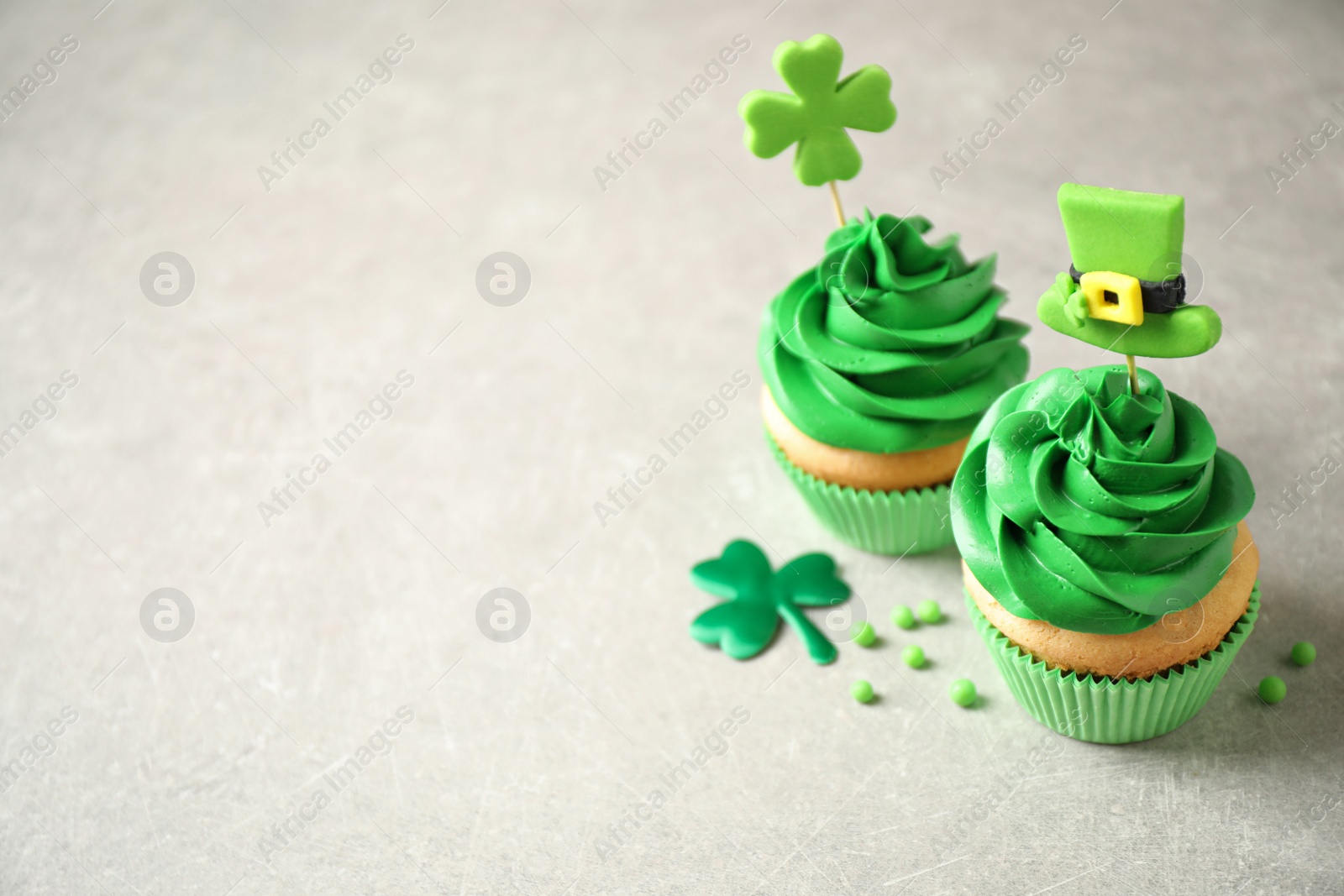 Photo of Delicious decorated cupcakes on light table, space for text. St. Patrick's Day celebration