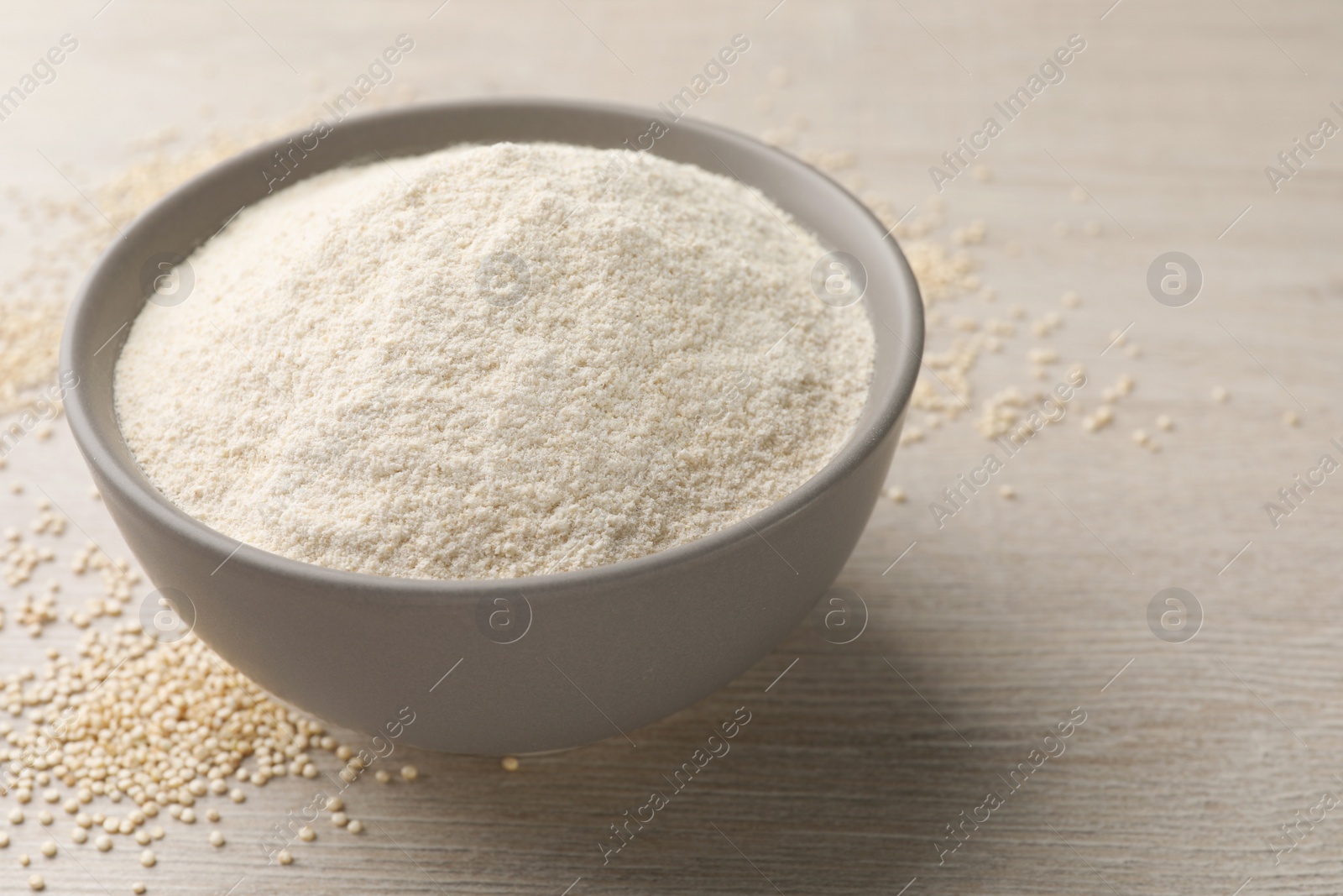 Photo of Ceramic bowl with quinoa flour and seeds on wooden table. Space for text