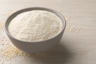 Photo of Ceramic bowl with quinoa flour and seeds on wooden table. Space for text