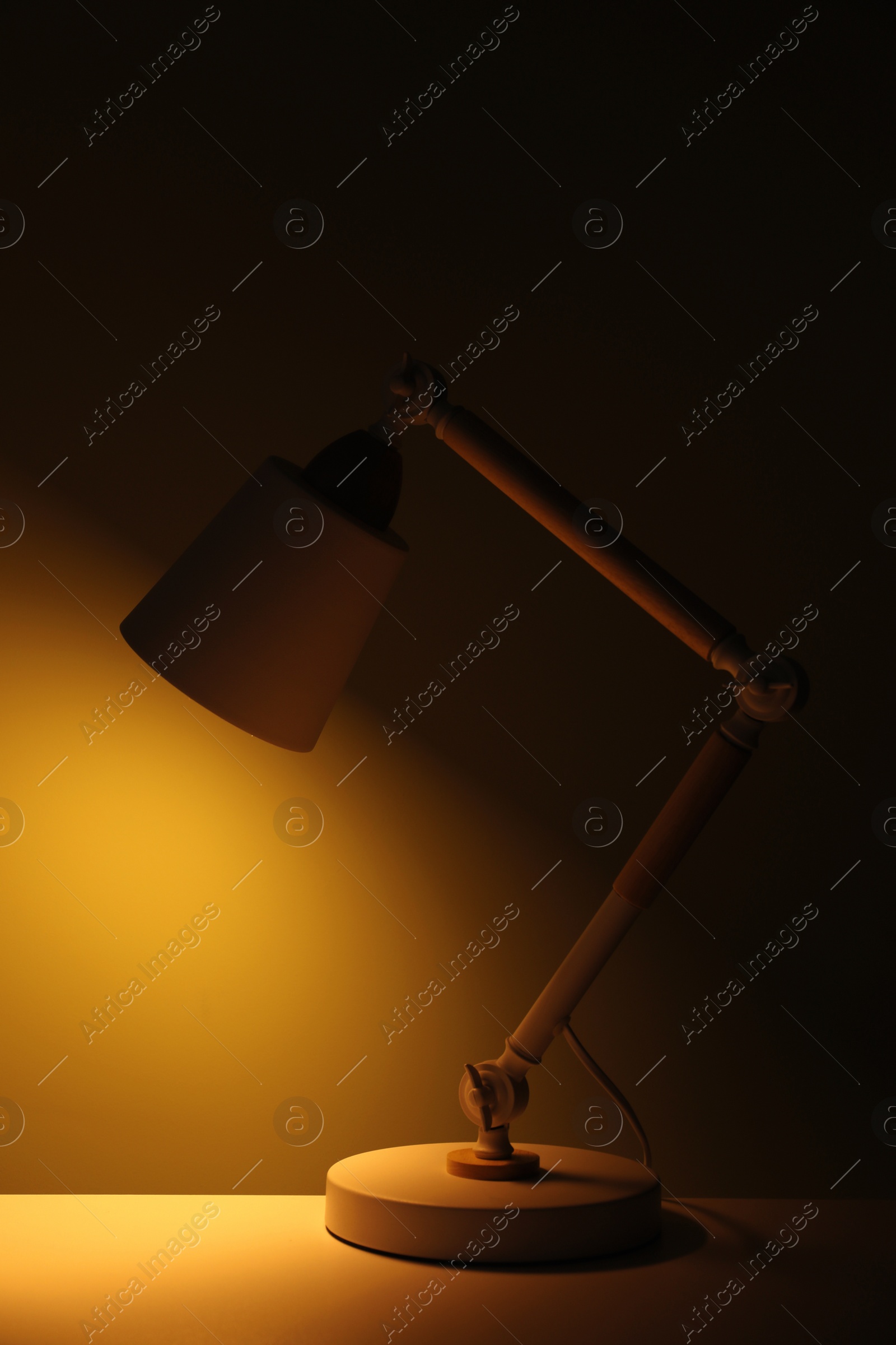 Photo of Stylish modern desk lamp on table at night