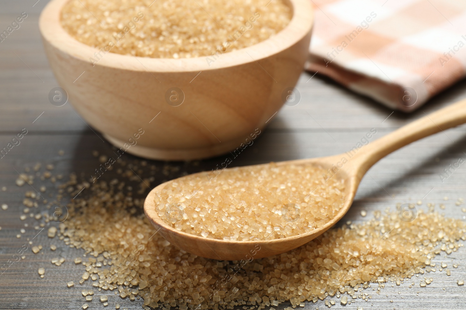 Photo of Brown sugar in bowl and spoon on wooden table, closeup