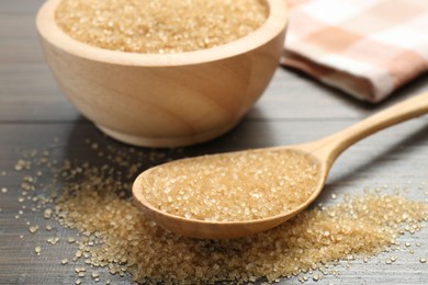 Photo of Brown sugar in bowl and spoon on wooden table, closeup