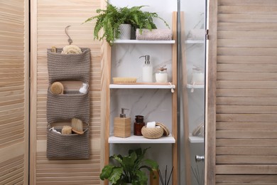Photo of Shelving unit and organizer with essentials in bathroom. Stylish accessory