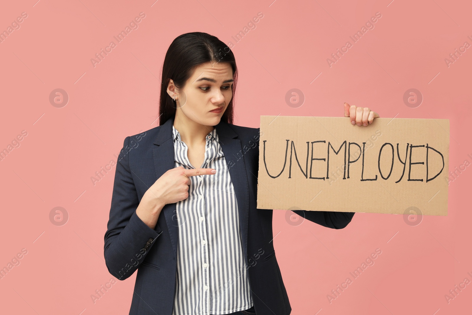 Photo of Unhappy woman holding sign with word Unemployed on pink background