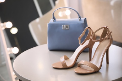 Photo of Stylish women's shoes and bag on table in modern boutique
