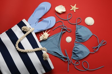 Photo of Stylish bag with beach accessories on red background, flat lay