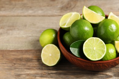 Photo of Tasty ripe limes in bowl on wooden table, closeup