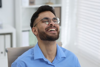 Photo of Portrait of handsome young man laughing in office