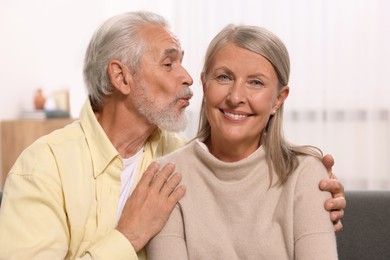 Photo of Senior man kissing his beloved woman at home