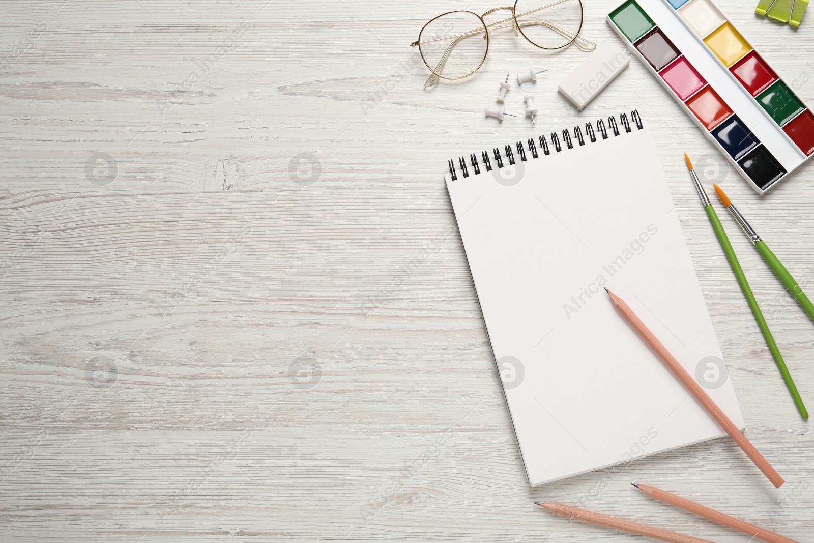 Photo of Flat lay composition with blank sketchbook on white wooden table. Space for text