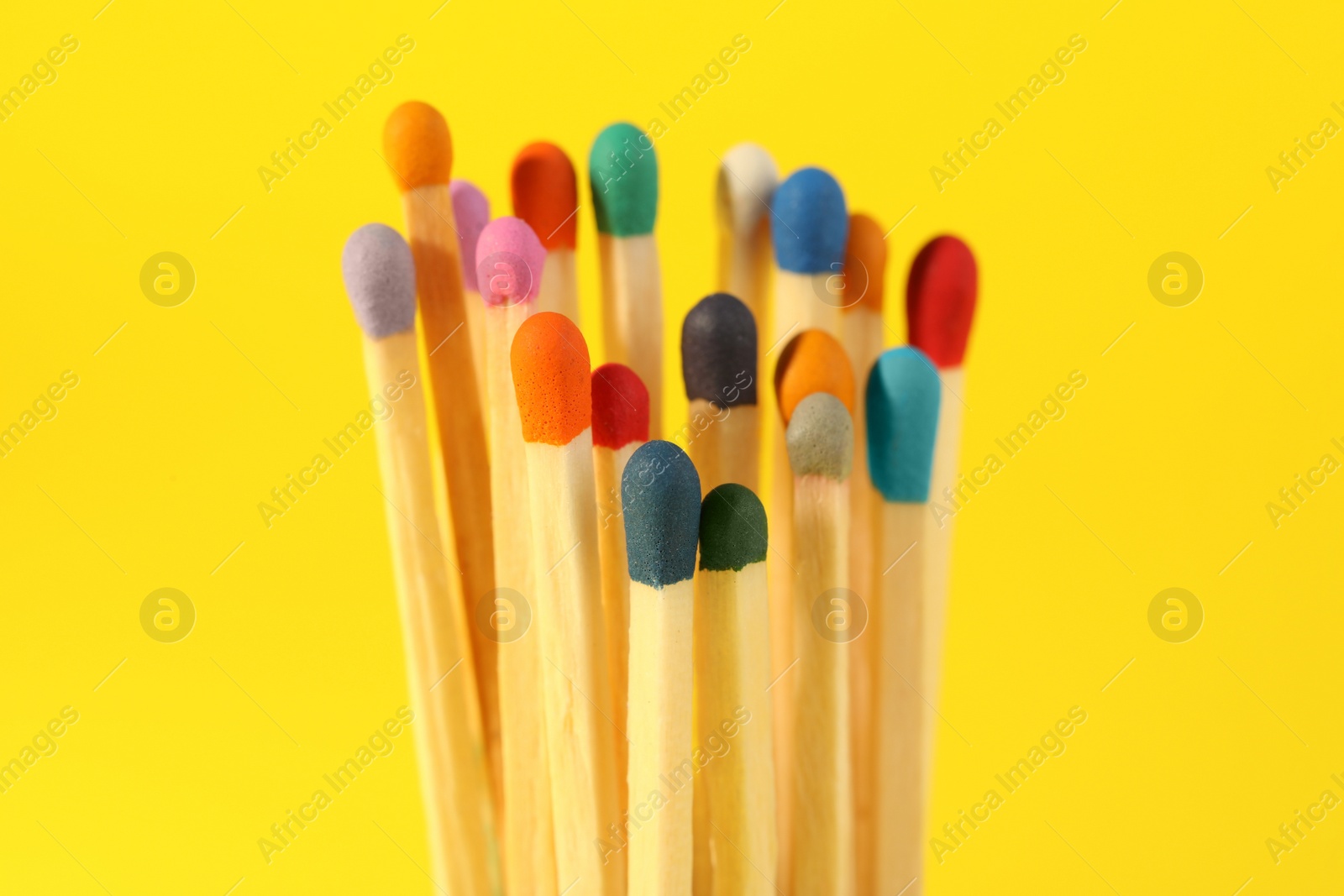 Photo of Matches with colorful heads on yellow background, closeup
