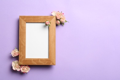 Photo of Flat lay composition with wooden photo frame and beautiful flowers on color background, space for text