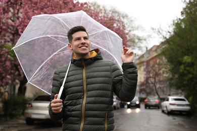 Handsome man with umbrella walking on spring day