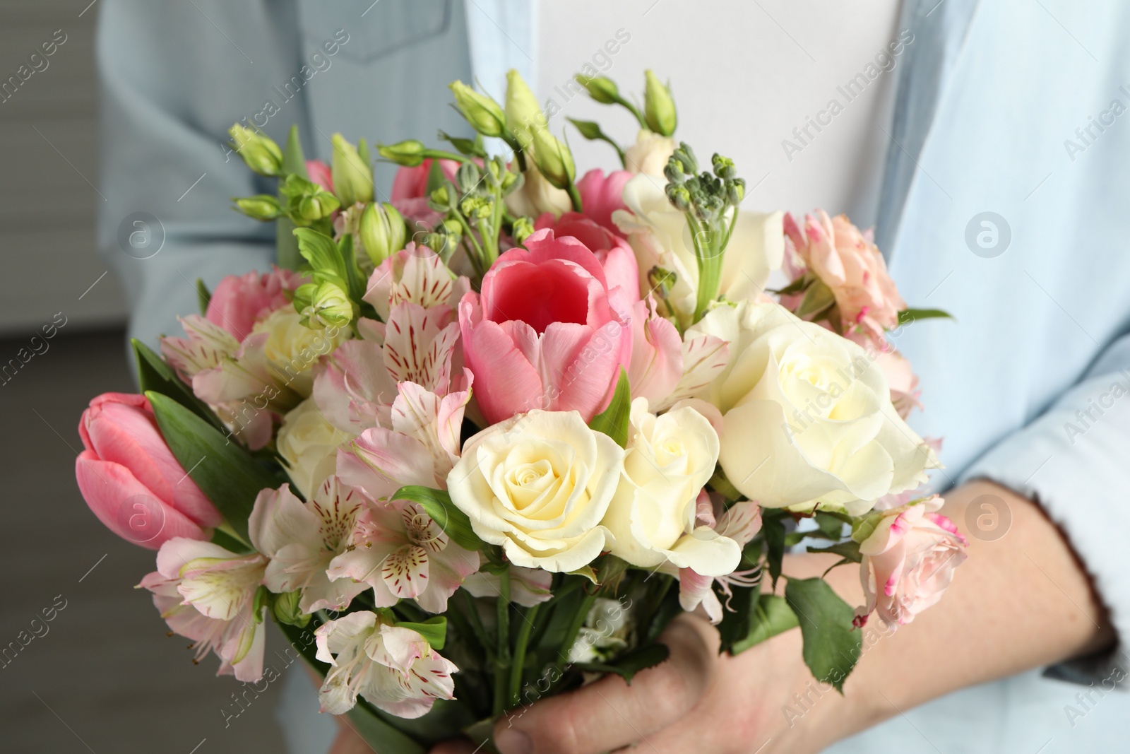 Photo of Man holding bouquet of beautiful flowers indoors, closeup