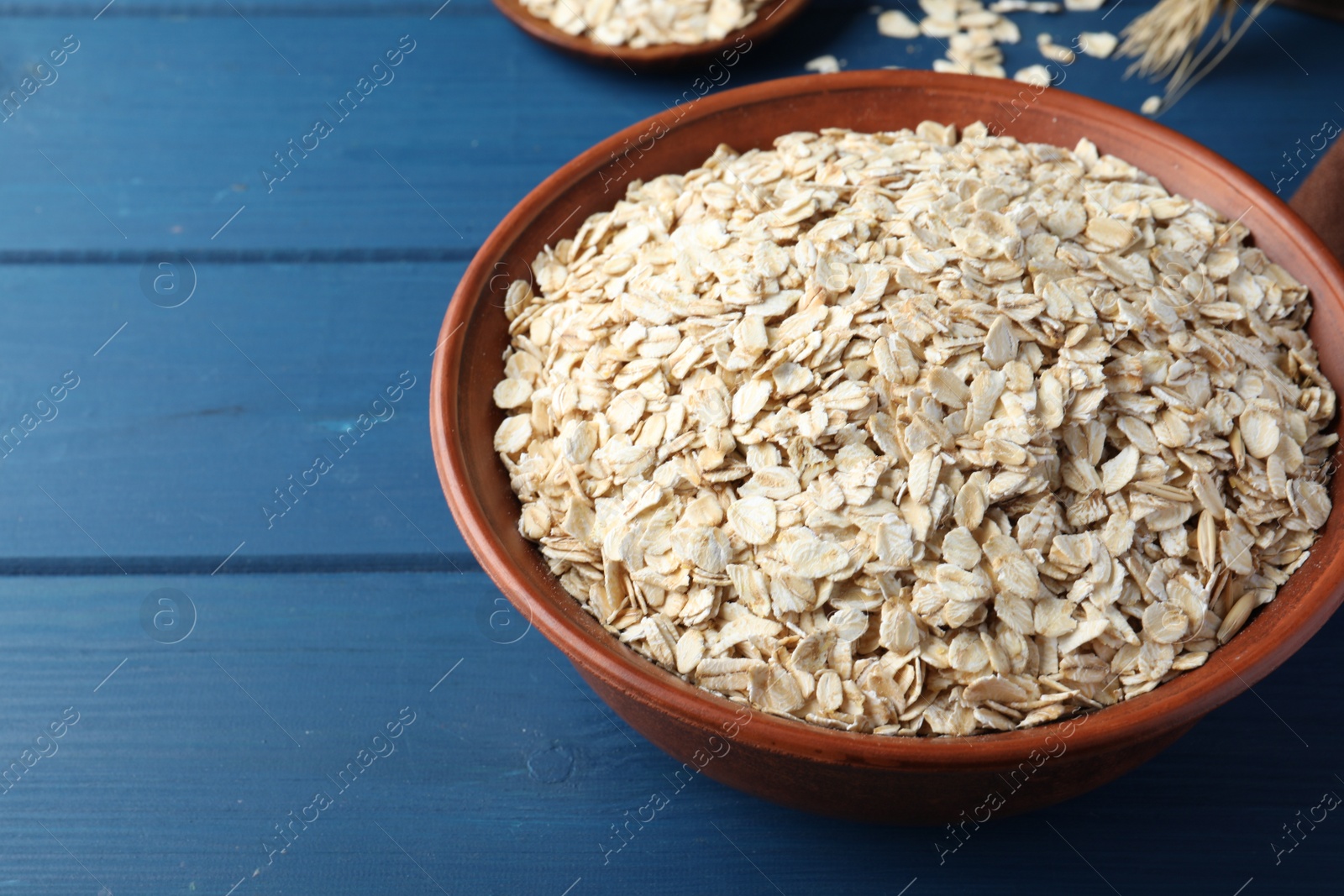 Photo of Bowl of oatmeal on blue wooden table, space for text