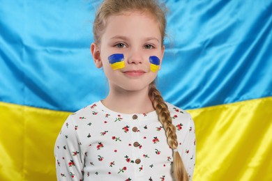 Little girl with face paint near Ukrainian flag